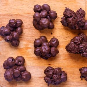 Chocolate covered blueberries on a wooden surface.