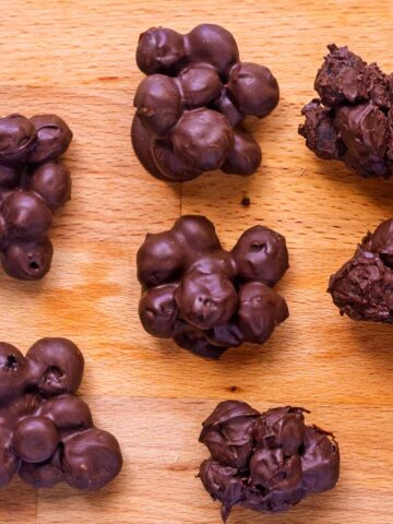 Chocolate covered blueberries on a wooden surface.