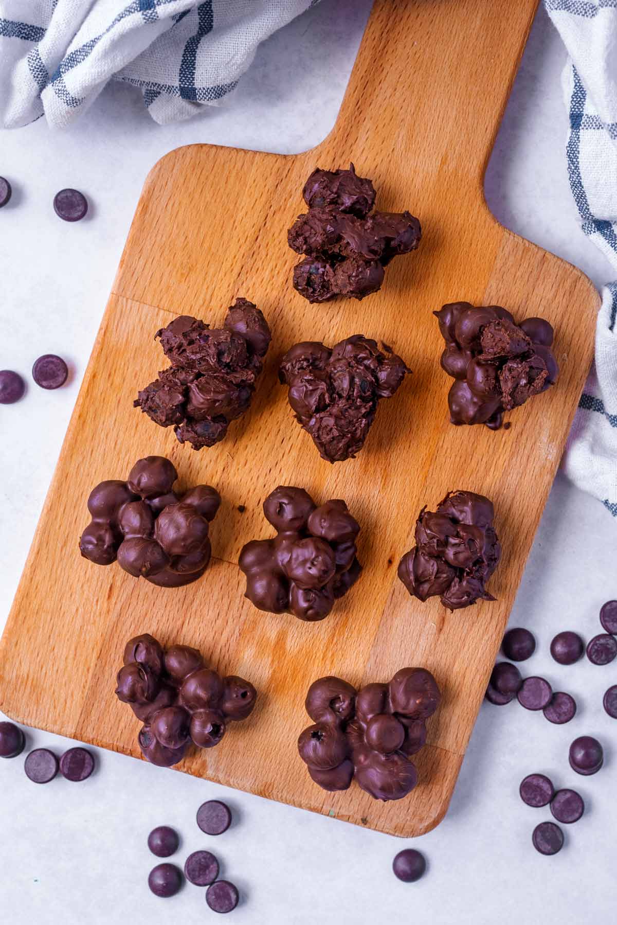 A wooden serving board with chocolate blueberries on it.