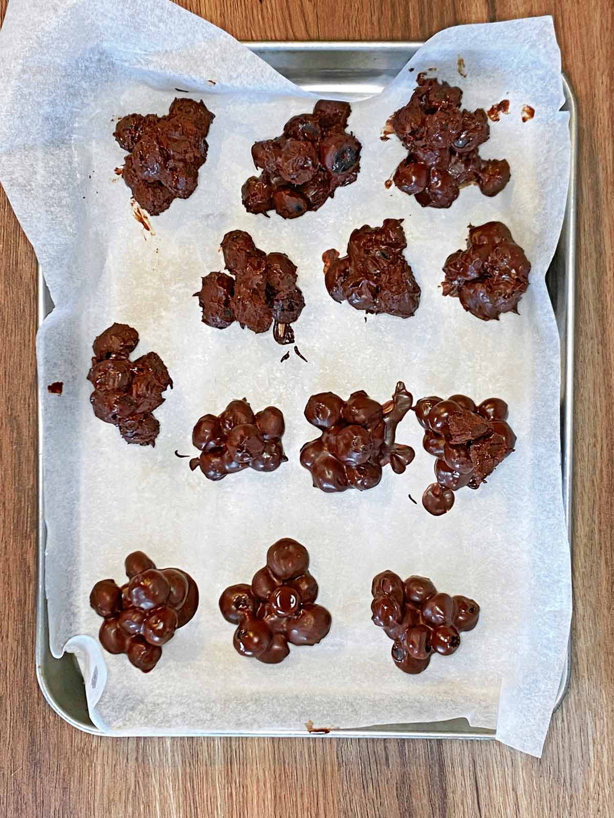 Piles of chocolate covered blueberries on a lined baking tray.