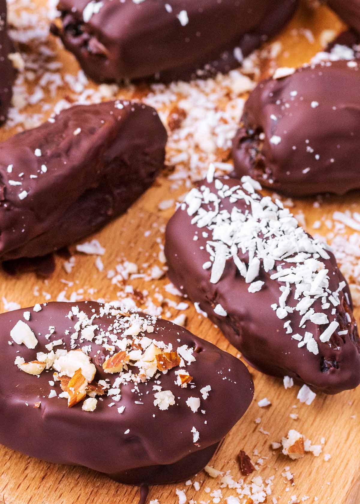 Dates covered in chocolate topped with crushed nuts and coconut.