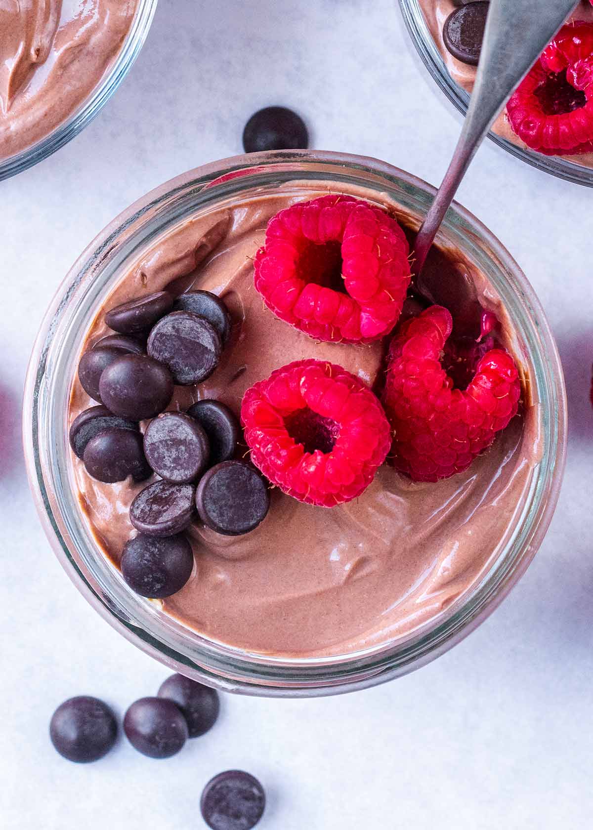Chocolate yogurt topped with raspberries and chocolate chips.