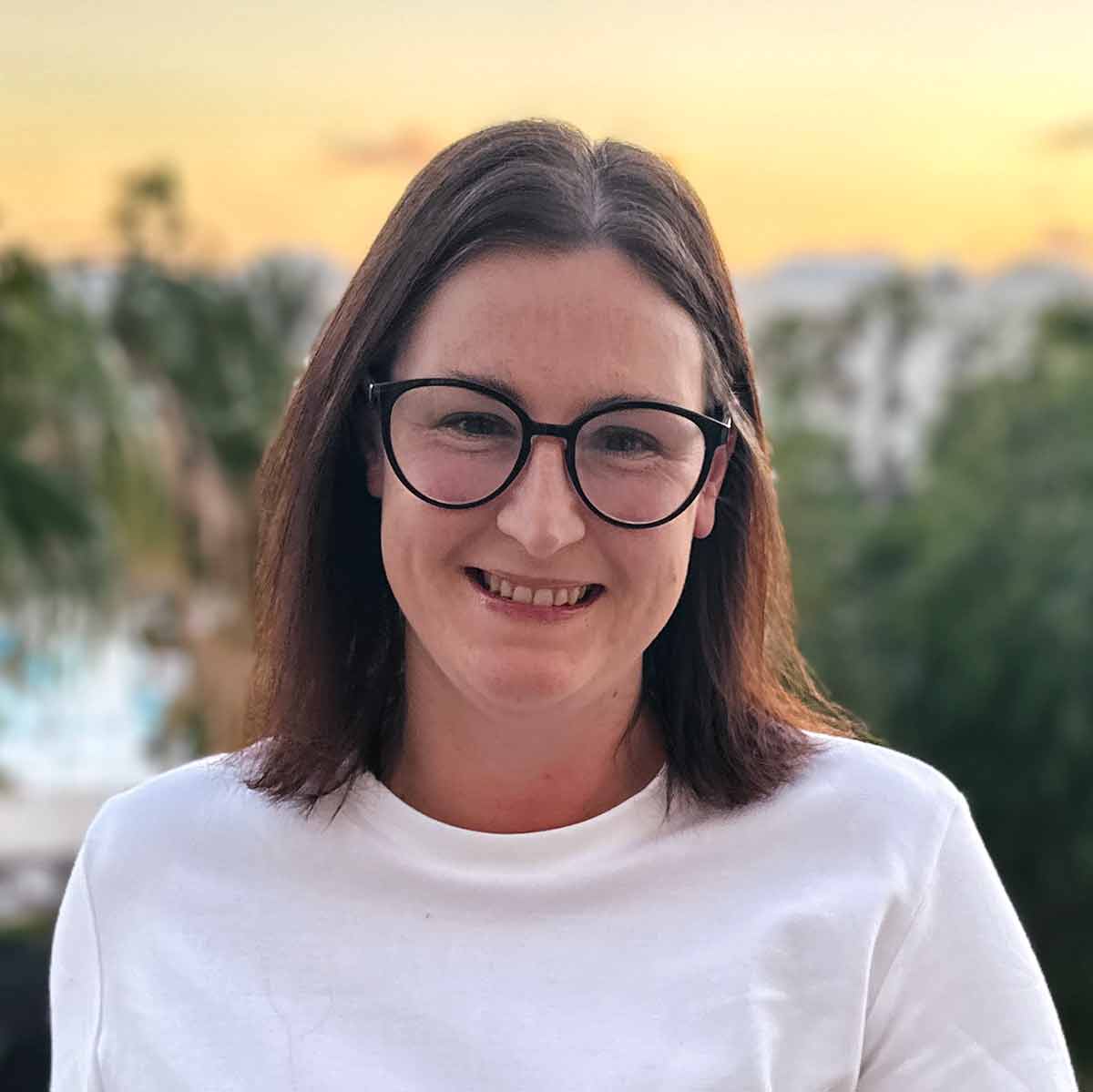 A headshot of Dannii with a sunset in the background.