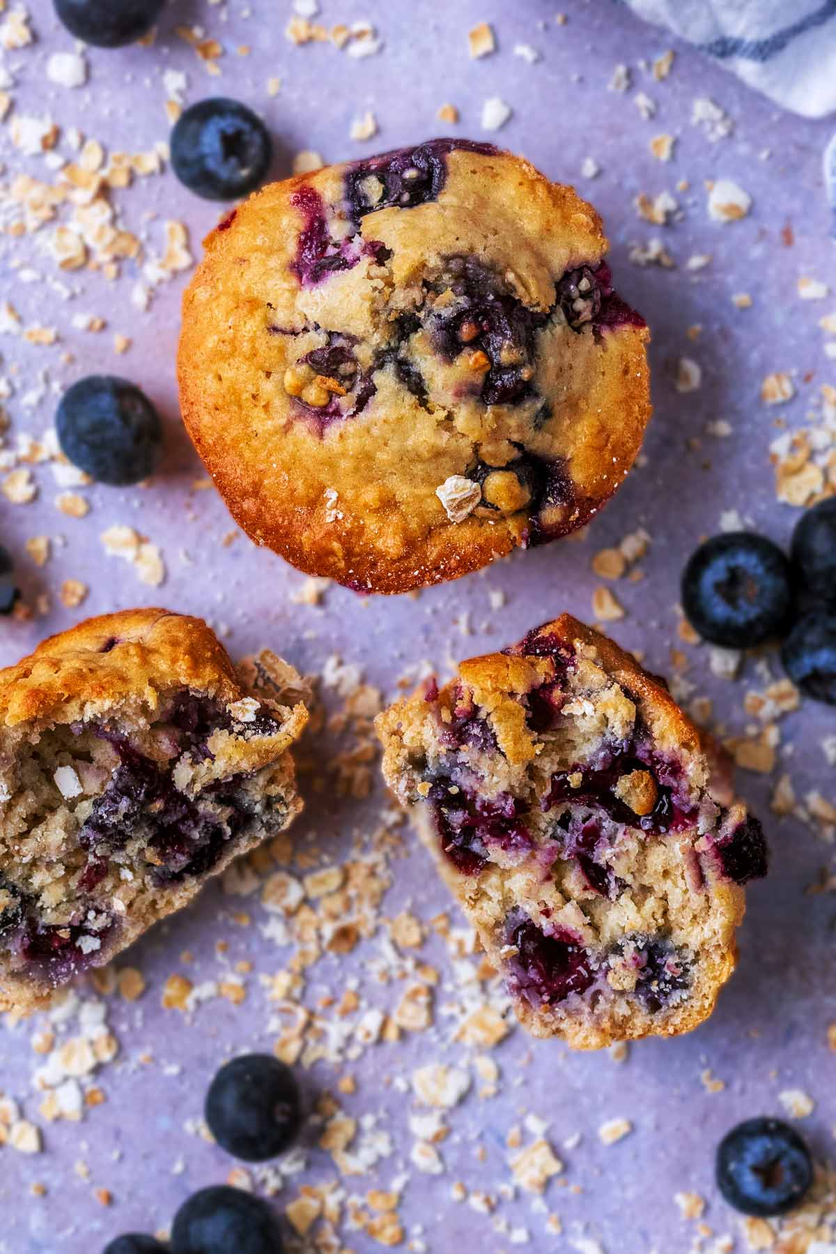 Two blueberry muffins, one is broken in half.