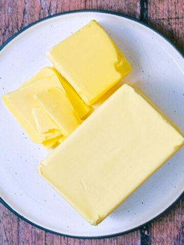 Butter, cut into pieces, on a white plate.