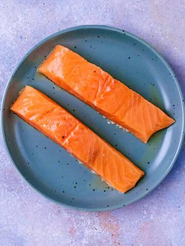 Two salmon fillets on a plate.