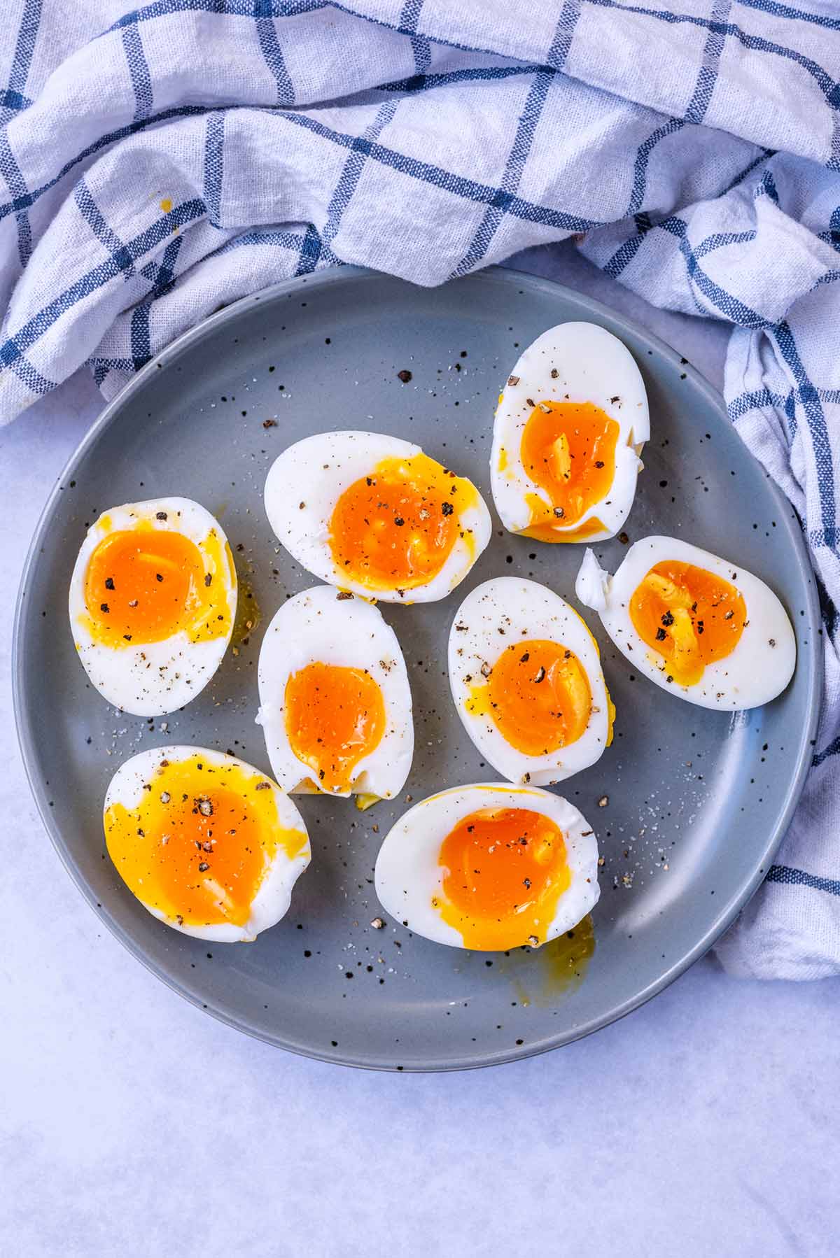 Eight boiled egg halves on a plate, all with runny yolks.