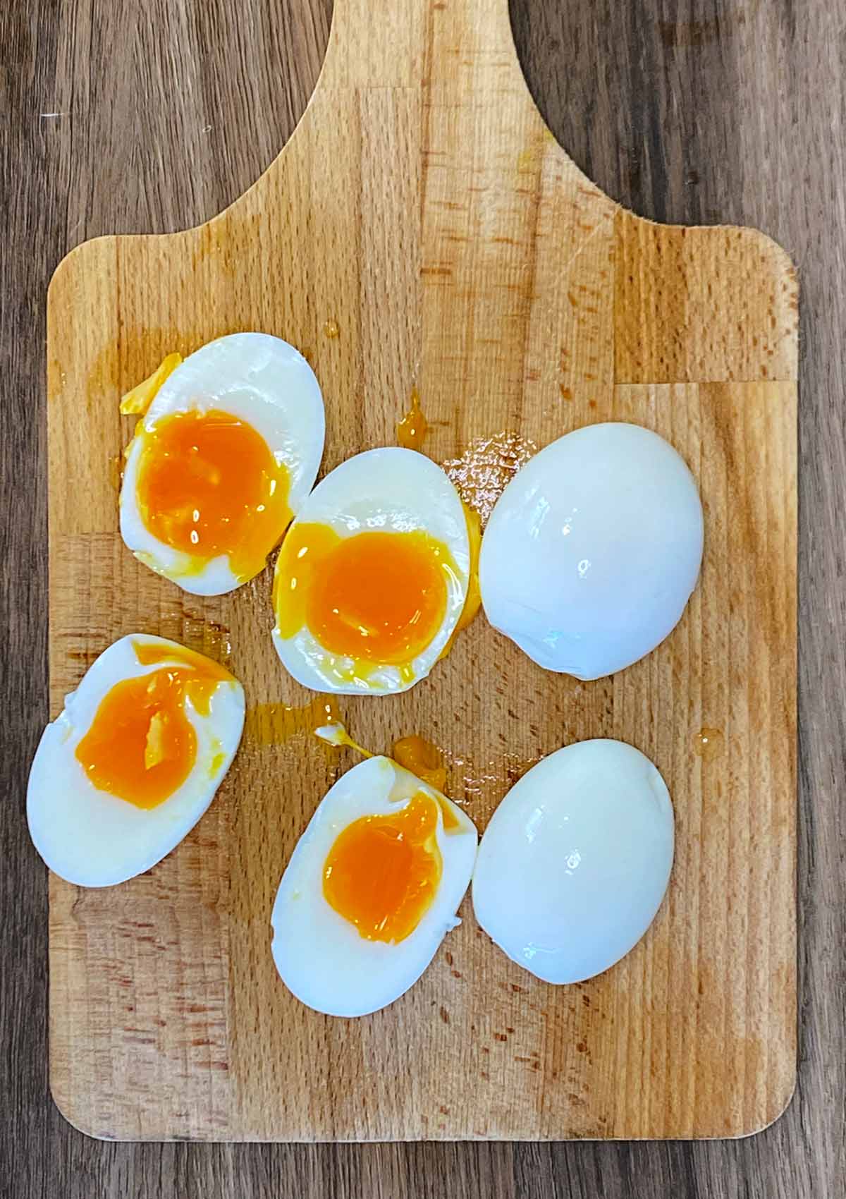 Halved boiled eggs on a wooden board.