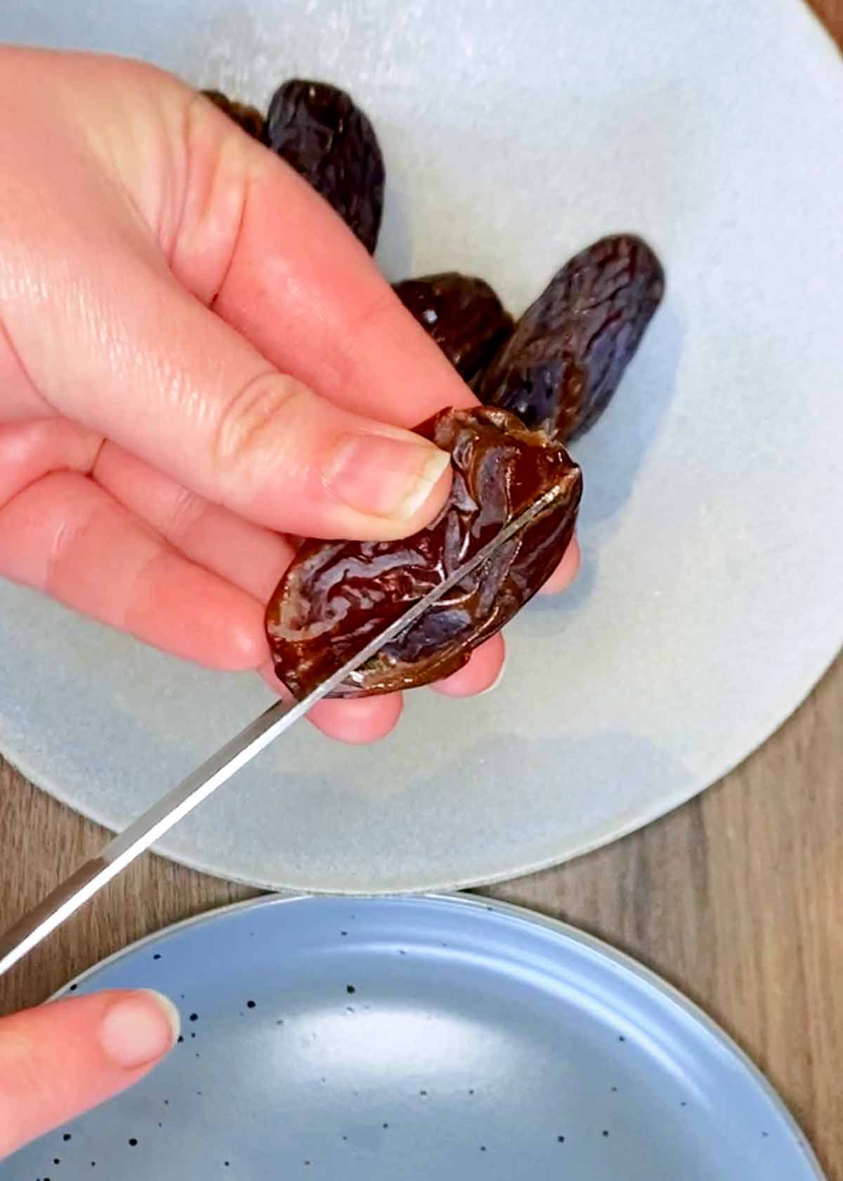 Someone cutting into a date with a knife.