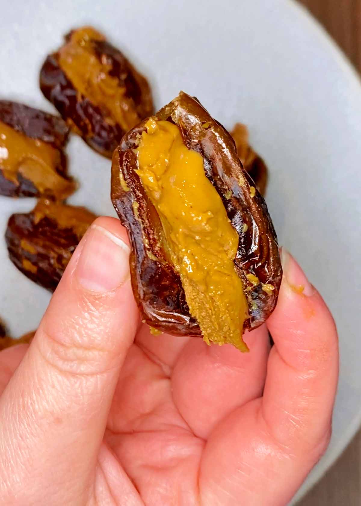 A hand holding a date stuffed with peanut butter.