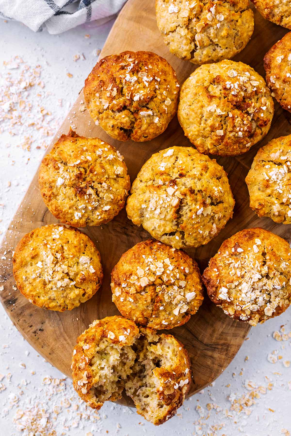 Banana muffins on a wooden board surrounded by scattered oats.