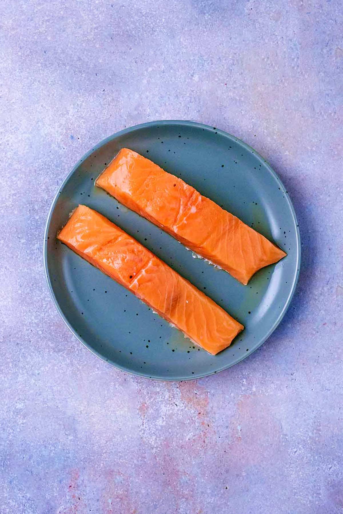 A plate with two salmon fillets on it.