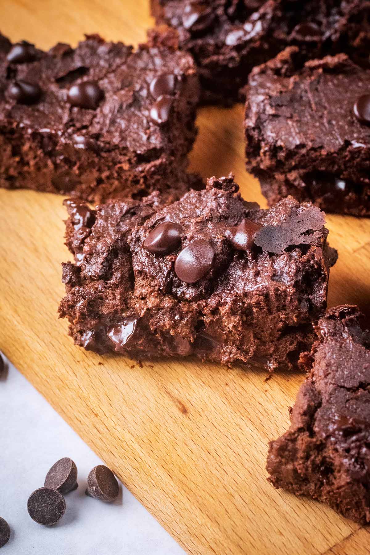 A chocolate brownie on a wooden serving board.