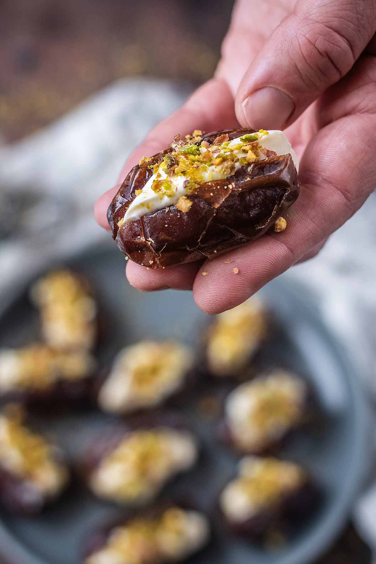 A hand holding a large date filled with a creamy filling.