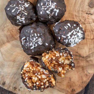 Five crispy date caramel balls with one cut open.