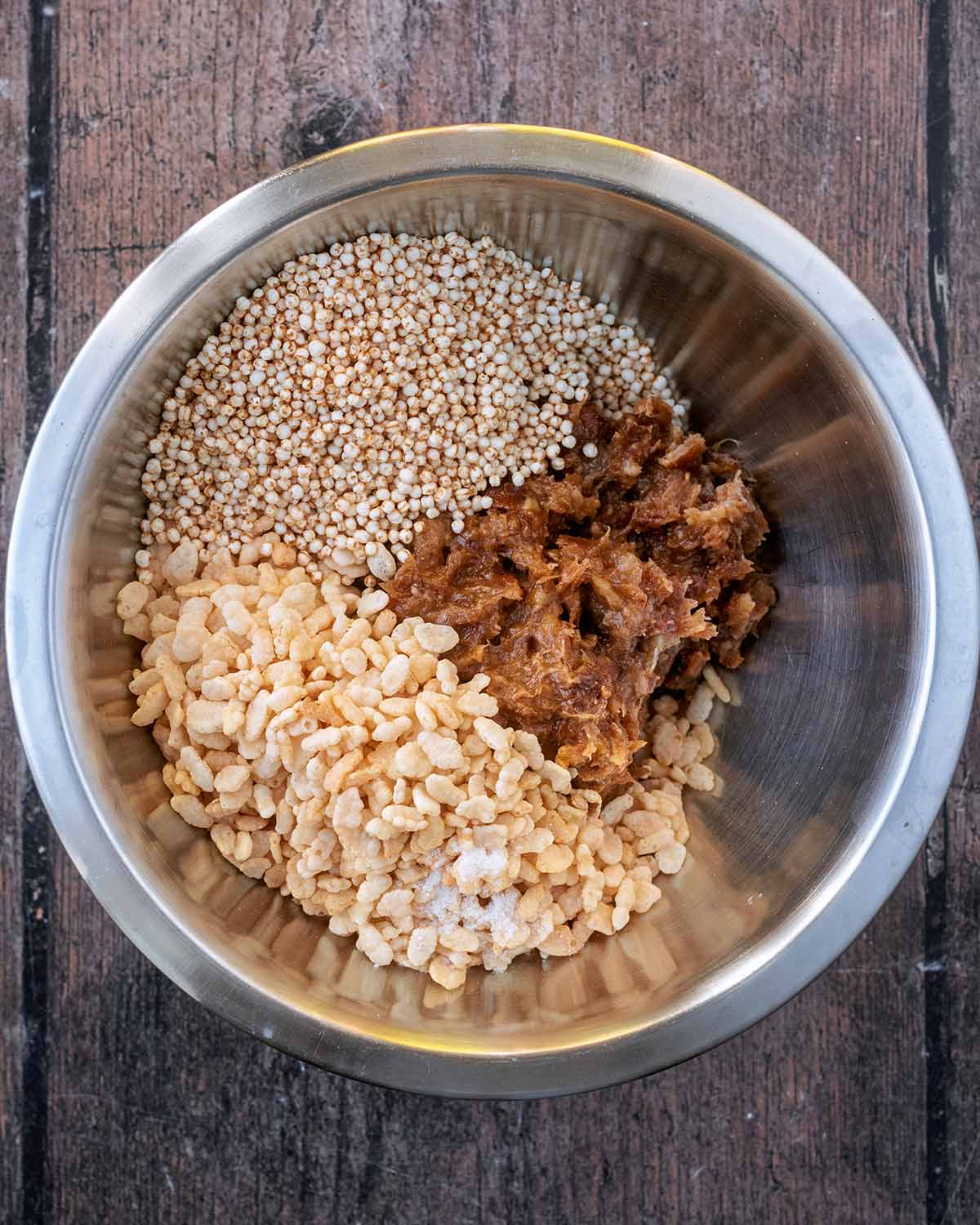 Date caramel, puffed rice and quinoa in a mixing bowl.
