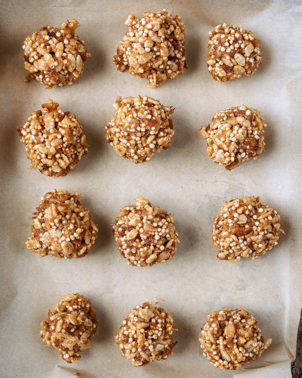Twelve crispy date balls on a lined baking sheet.