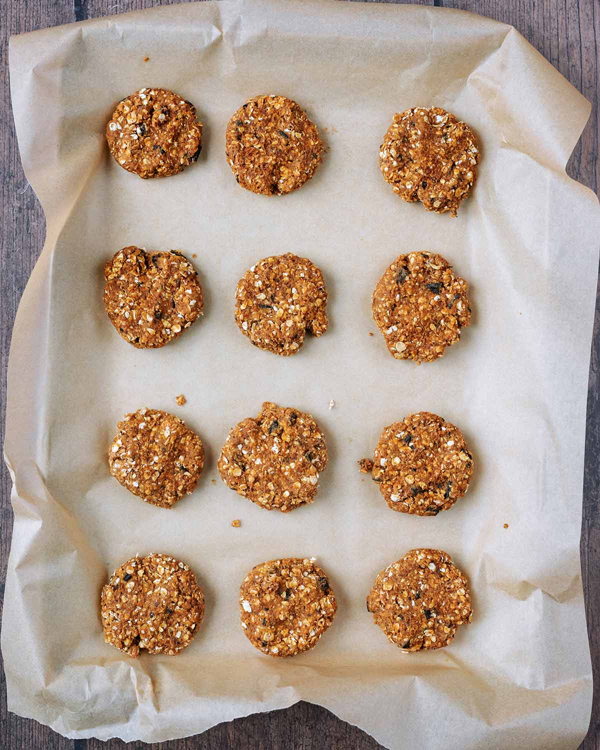 Twelve balls of cookie dough on a lined baking sheet.